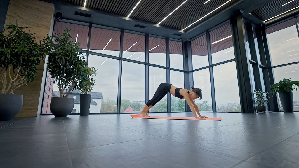 Žena u joga pozi na prostirci, u modernoj sali, u tekstu o joga ili pilates vežbama